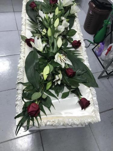 Естествени цветя аранжирани върху ковчег