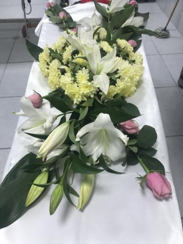 Естествени цветя аранжирани върху ковчег