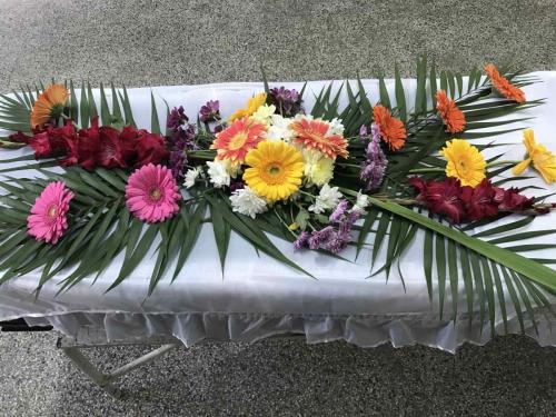 Естествени цветя аранжирани върху ковчег